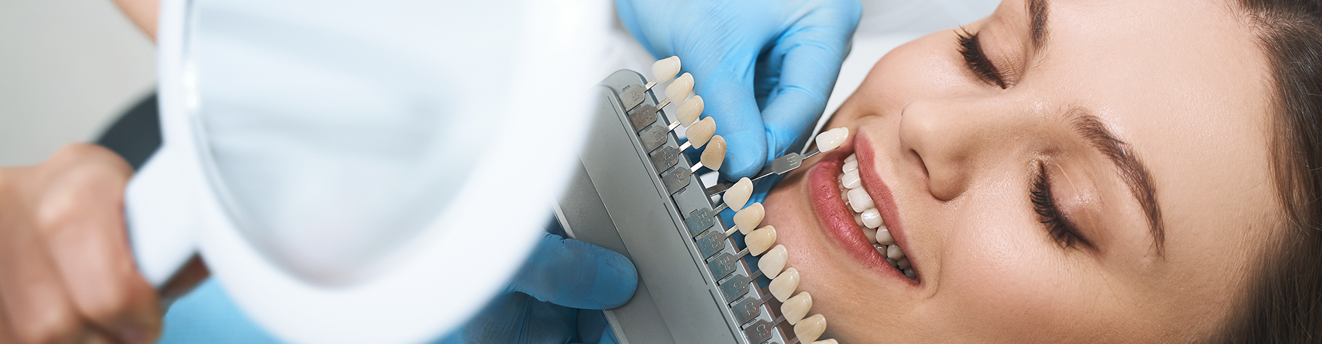 tooth shade-matching tool held against woman's teeth